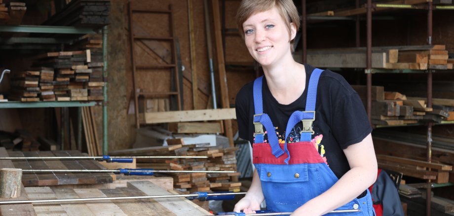 Vanessa Göcke leimt Holzlatten zusammen. Dies war Teil ihrer Tätigkeit in der Tischlerei des Denkmalpflege-Werkhofs.