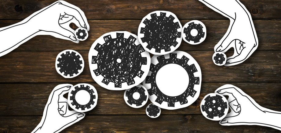 Paper hands collecting gears, creating whole mechanism